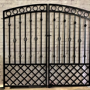 May include: Black metal double gate with an arched top and decorative accents. The gate features a diamond-shaped lattice design at the bottom.