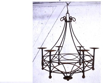 May include: A rustic, wrought iron chandelier with six candle holders. The chandelier has a circular base and a decorative, swirling design.