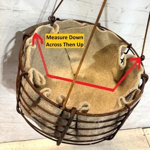 May include: A round hanging basket with a rusted metal wire frame and a beige felt liner. The interior features a yellow rectangular graphic with the black text Measure Down Across Then Up, accompanied by red arrows indicating measurement points.