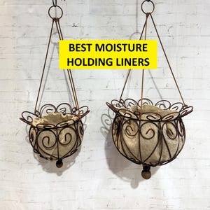 May include: Two hanging planters with a brown, wrought-iron design. Each planter has a round shape with a decorative scroll pattern and a beige liner. The planters are suspended by thin metal wires and have a wooden ball at the bottom. The text "BEST MOISTURE HOLDING LINERS" is in a yellow rectangle.