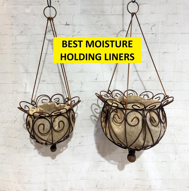 May include: Two hanging planters made of dark brown rusted metal wire with decorative scrollwork patterns. Each basket contains a light tan fabric liner. The text BEST MOISTURE HOLDING LINERS is displayed in black on a yellow rectangular background.