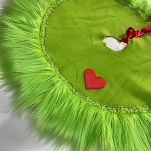 May include: Green fuzzy Christmas tree skirt with a red heart and a black and white swirl design.