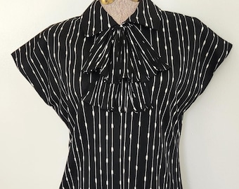 Blusa plisada estilo Ascot con estampado geométrico en blanco y negro de Mardi Modes, estilo retro de los años 50 y 60, de manga corta para mujer.