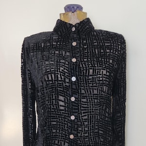 May include: A long-sleeved black shirt featuring a semi-sheer fabric with a raised, velvet-like grid pattern. The garment has a classic collar, a full-length front button placket with light-colored buttons, and buttoned cuffs on the sleeves.