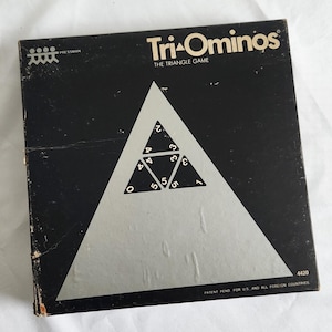 May include: A black box game called "Tri-Ominos: The Triangle Game". The box features a silver triangle with numbers 0-5 on each point.
