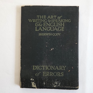 May include: A vintage, rectangular book with a dark cover. The title reads "THE ART of WRITING & SPEAKING The ENGLISH LANGUAGE" and "DICTIONARY of ERRORS" in gold lettering. The author's name, SHERWIN CODY, is also visible.