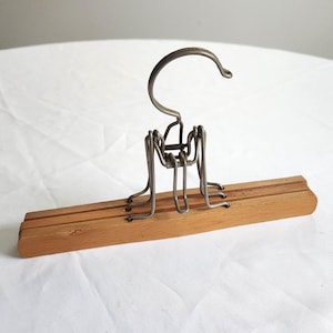 May include: A wooden hanger with a metal hook and a wire frame. The hanger is designed to hold multiple items of clothing.