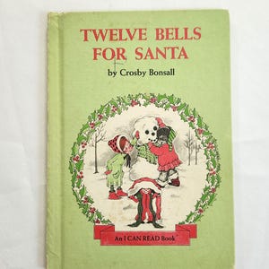 May include: A vintage children's book titled "Twelve Bells for Santa" by Crosby Bonsall. The cover is light green with illustrations of children and a snowman inside a holly wreath. The book is part of the "An I CAN READ Book" series.