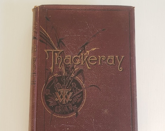 May include: A burgundy hardback book with gold lettering that reads "Thackeray" on the spine and cover. The cover features a gold design of a circle with a stylized "W" inside and leaves around it.