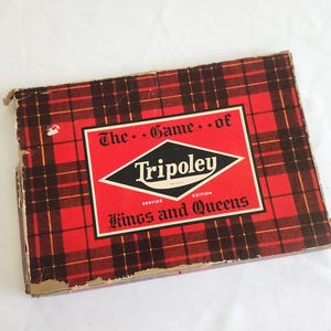 May include: A rectangular board game box featuring a red and black plaid pattern. The center label is red with a black diamond shape containing the white text Tripoley. Additional text reads The Game of and Kings and Queens Service Edition.