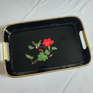 May include: Black serving tray with a gold rim and a floral design featuring a hummingbird and red flowers. The tray has two wooden handles.