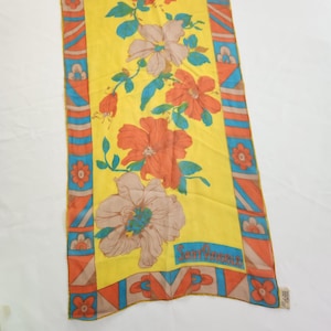 May include: A vintage yellow scarf with a floral pattern. The scarf features large orange and tan flowers with blue accents. The border has a geometric design in orange, blue, and tan. The text "Sant'Angelo" is visible.