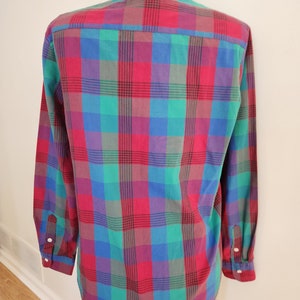 May include: A long-sleeved button-down shirt with a plaid pattern in shades of red, green, blue, and purple.