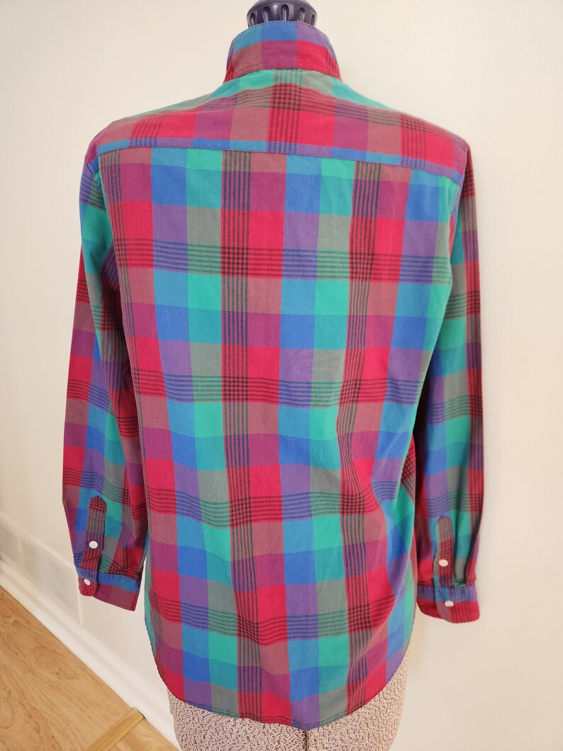 May include: A long-sleeved button-down shirt with a plaid pattern in shades of red, green, blue, and purple.