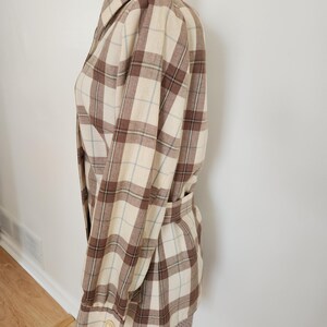 May include: A beige and brown plaid jacket with a matching belt. The jacket has a collared neckline and buttoned cuffs. The plaid pattern includes light blue lines. The jacket is displayed on a mannequin.