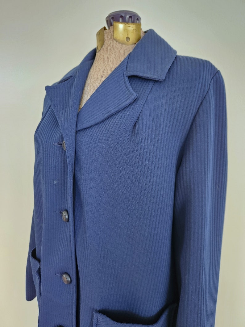 May include: A navy blue ribbed long-sleeved jacket with a button-up front and two pockets.