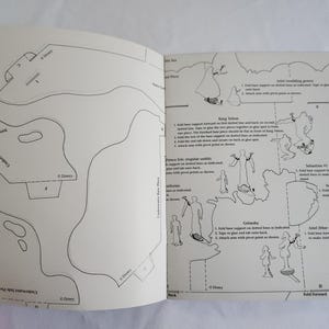 Puede incluir: Un libro de manualidades en papel con plantillas de arte lineal en blanco y negro de personajes de Disney, incluyendo al Rey Trit&oacute;n, el Pr&iacute;ncipe Eric, Sebasti&aacute;n y Ariel. Las p&aacute;ginas contienen instrucciones, l&iacute;neas de pliegue y formas.