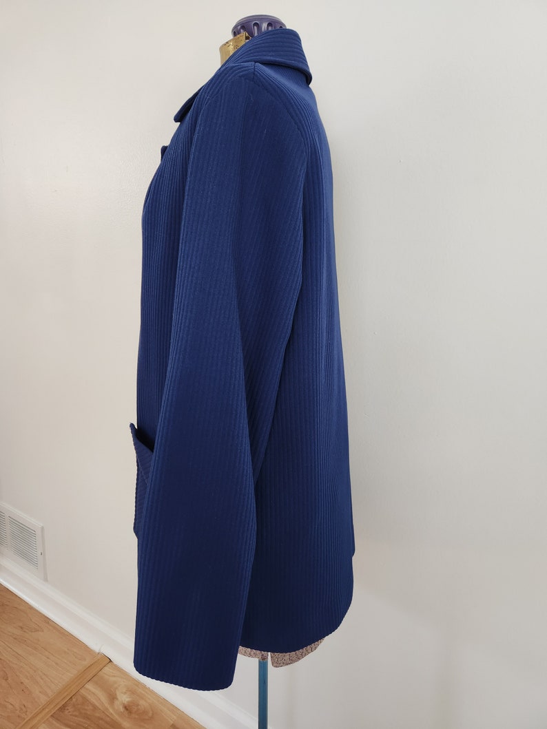 May include: A navy blue blazer with a ribbed texture and a single pocket on the left side.