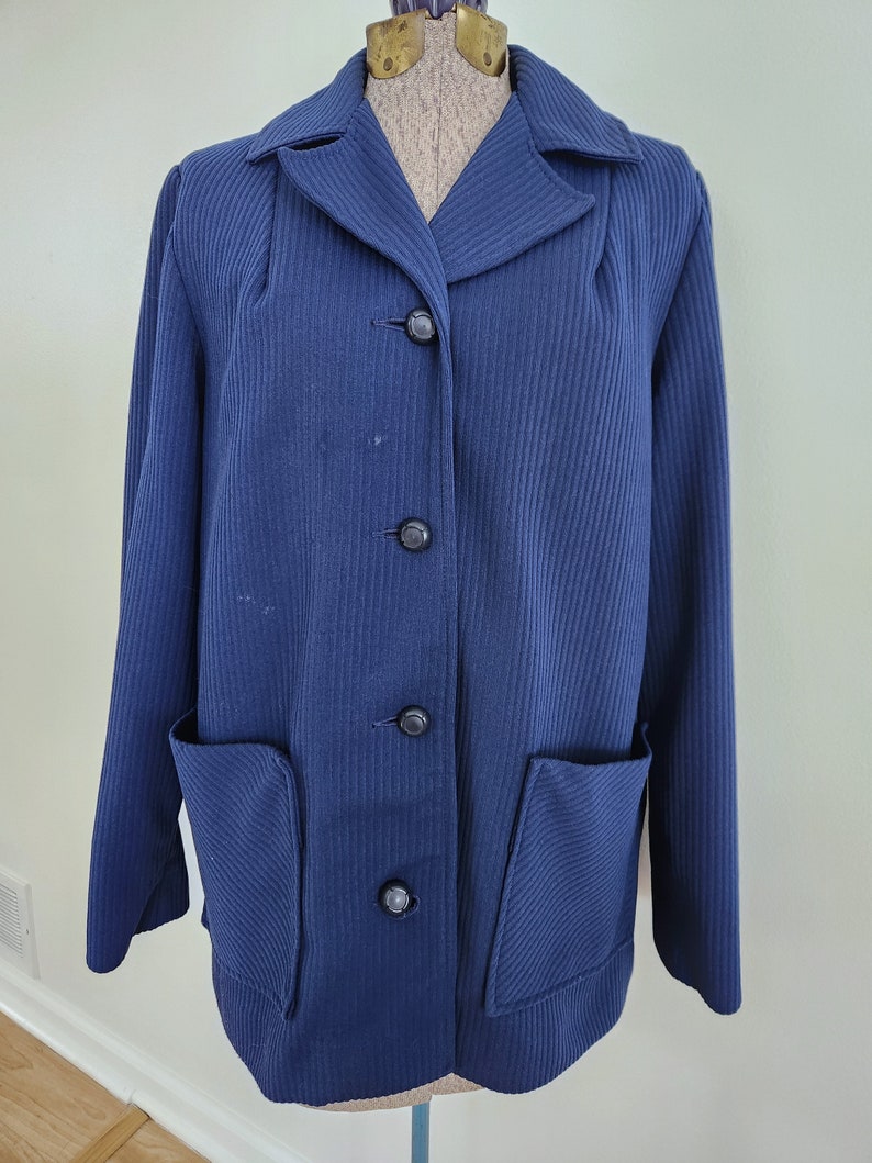 May include: A navy blue blazer with a ribbed texture and four black buttons. The blazer has two patch pockets on the front.