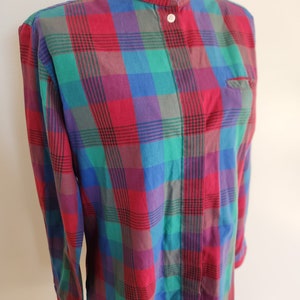 May include: A long-sleeved plaid shirt with a mandarin collar and button closure. The shirt is red, green, blue, and purple.