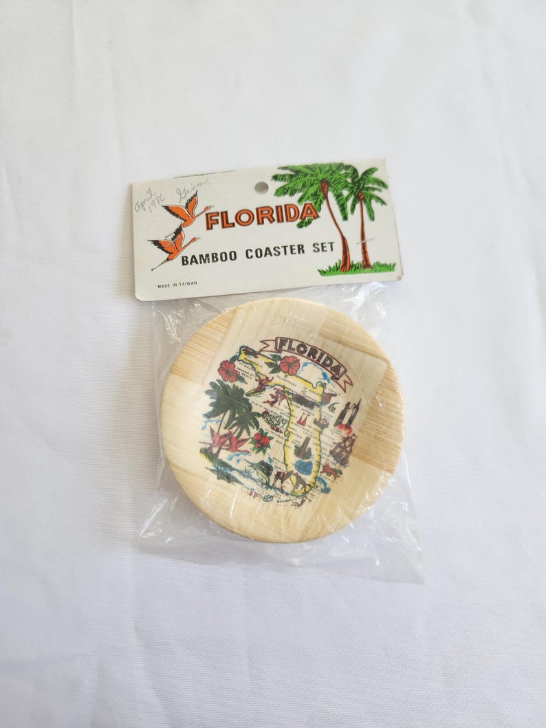 Puede incluir: Un juego de posavasos de bamb&uacute; con un posavasos redondo con un dise&ntilde;o de mapa de Florida. El embalaje incluye una etiqueta con la palabra "FLORIDA" e ilustraciones de palmeras. El posavasos est&aacute; hecho de bamb&uacute; de color claro.