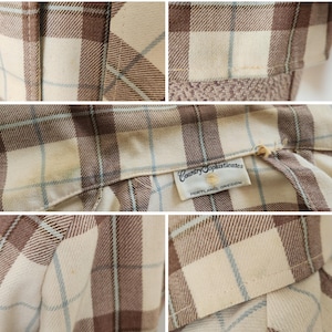 May include: Close-up of a vintage plaid shirt in cream, brown, and light blue. The shirt features a classic plaid pattern and a label that reads "Country Sophisticates, Portland, Oregon."