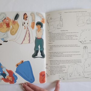 Puede incluir: Una p&aacute;gina de libro de manualidades de papel con personajes recortables que incluyen un chef, una novia con vestido blanco y un novio con camisa beige y pantalones verde azulado. La p&aacute;gina incluye instrucciones de montaje para un barco.