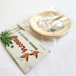 Puede incluir: Un juego de posavasos de bamb&uacute; con tem&aacute;tica de Florida. Los posavasos est&aacute;n en un paquete de pl&aacute;stico transparente. El embalaje incluye una etiqueta con las palabras "Florida Bamboo Coaster Set" e ilustraciones de palmeras y flamencos.