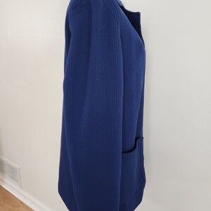 May include: A navy blue blazer with a single pocket on the right side. The blazer has a ribbed texture and a collar.