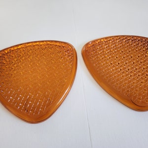 May include: Two amber-colored, triangular-shaped glass pieces with a diamond-shaped pattern.