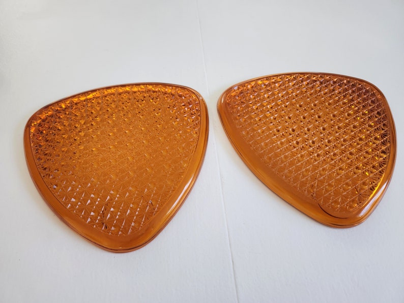 May include: Two amber-colored, triangular-shaped glass pieces with a diamond-shaped pattern.