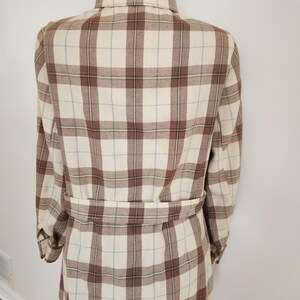 May include: A beige and brown plaid jacket with a matching belt. The jacket features a classic collar and long sleeves. The plaid pattern includes thin light blue lines. The jacket is displayed on a mannequin.