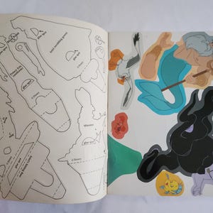 Puede incluir: Un libro de manualidades de Disney con contornos en blanco y negro para recortar figuras del Pr&iacute;ncipe Eric y Ariel en la p&aacute;gina izquierda, e ilustraciones a color del Rey Trit&oacute;n, &Uacute;rsula, Flounder y Sebasti&aacute;n en la p&aacute;gina derecha.