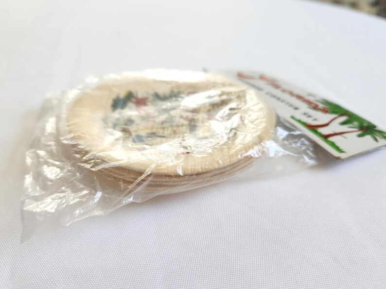 Puede incluir: Un juego de posavasos redondos con una imagen colorida, empaquetados en pl&aacute;stico transparente. Los posavasos parecen estar hechos de madera de color claro. Una etiqueta con texto y una ilustraci&oacute;n de palmera es visible.