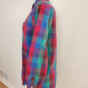 May include: A long-sleeved button-down shirt with a plaid pattern in shades of red, blue, green, and purple.