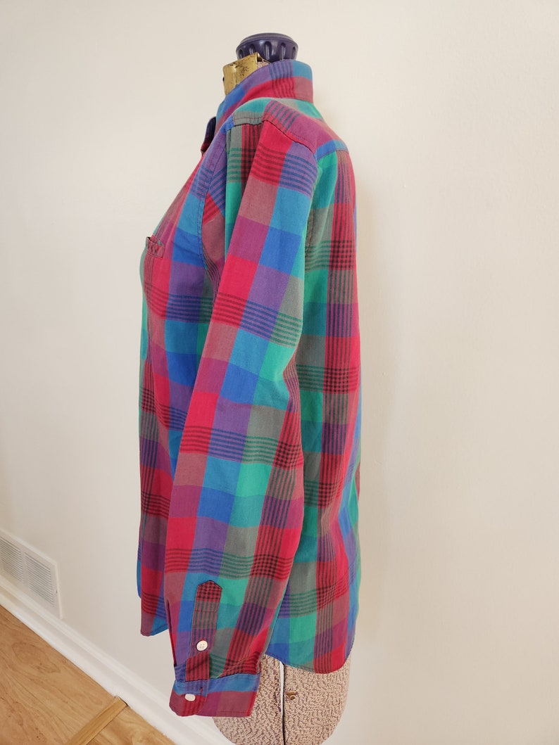 May include: A long-sleeved button-down shirt with a plaid pattern in shades of red, blue, green, and purple.
