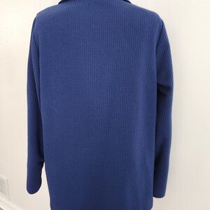 May include: A navy blue blazer with a ribbed texture. The blazer has a collar and long sleeves.
