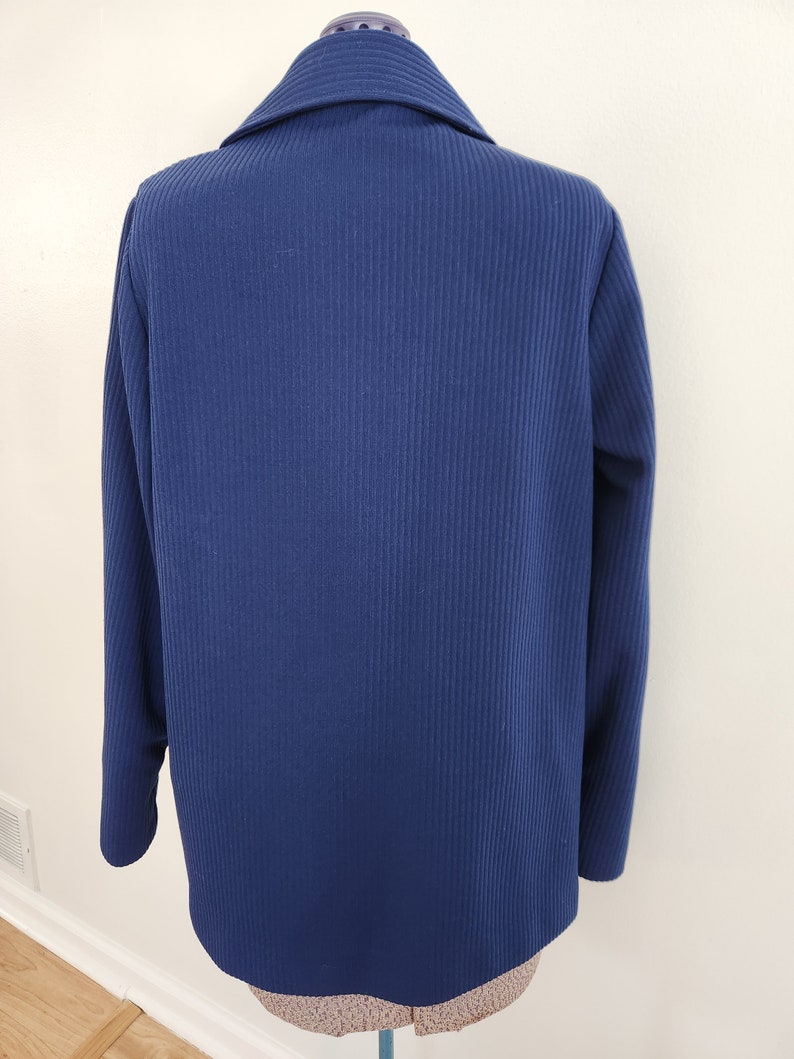 May include: A navy blue blazer with a ribbed texture. The blazer has a collar and long sleeves.