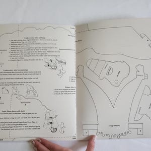 Puede incluir: Una hoja de instrucciones de papel con dibujos de l&iacute;neas negras y texto para ensamblar personajes de Disney. La p&aacute;gina incluye diagramas para Ariel bajo el agua, Ariel nadando, Ariel con vestido azul, el Pr&iacute;ncipe Eric y Max, con pesta&ntilde;as etiquetadas.