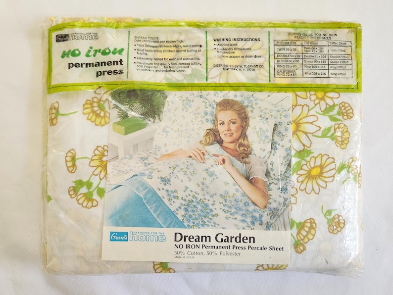 May include: A sealed package of Grants Home Dream Garden no-iron permanent press percale sheets. The packaging features a woman on a bed with floral sheets. The sheets have a white background with yellow and green flowers and blue floral accents.