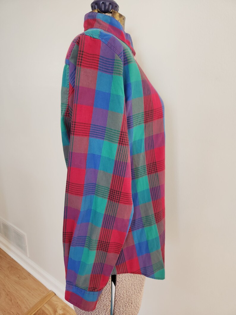 May include: A long-sleeved button-down shirt with a plaid pattern in shades of red, green, blue, and purple.