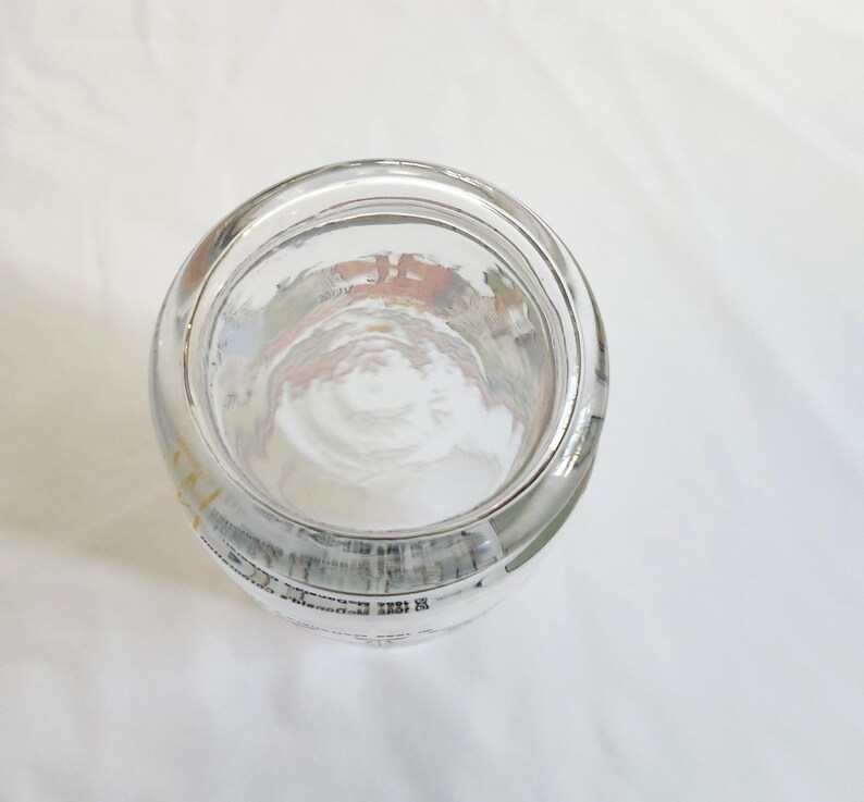 May include: A clear glass jar with a wide mouth and a rounded bottom. The jar has a white label with black text.