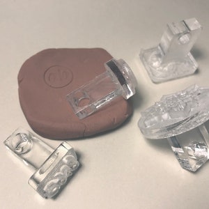 May include: Four clear plastic stamps with different designs. One stamp is a rectangle with the word "BOSS" in raised letters. Another stamp is a rectangle with a circular design. The third stamp is a rectangle with a raised design. The fourth stamp is a circular stamp with a raised design.