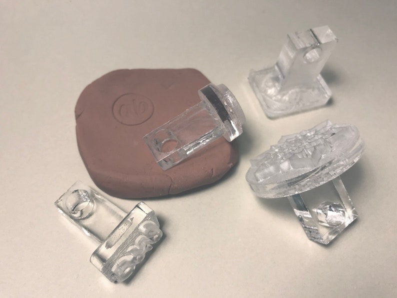 May include: Four clear plastic stamps with different designs. One stamp is a rectangle with the word "BOSS" in raised letters. Another stamp is a rectangle with a circular design. The third stamp is a rectangle with a raised design. The fourth stamp is a circular stamp with a raised design.