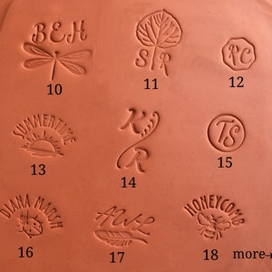 May include: Close-up of 18 different clay stamps with various designs, including a dragonfly, a leaf, initials, a bee, a ladybug, a feather, and a sun. The stamps are numbered 10 through 18.