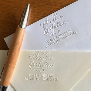 May include: Two white envelopes with a raised embossed design. The top envelope has the text "Pauline & Julien" and the address "1565 S. SUMNER AVE LA SALLE, MICHIGAN 48145". The bottom envelope has the same design and text.