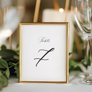 Peut inclure: Une carte de numéro de table avec un cadre doré, le mot "Table" et le numéro "7" écrits en calligraphie élégante.