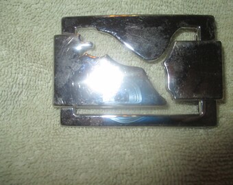 May include: A silver metal belt buckle with a cutout design of a mountain range.