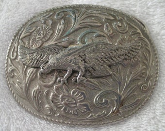 May include: Silver-toned belt buckle with an eagle design and floral accents.