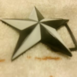 May include: A black and white star-shaped belt buckle.